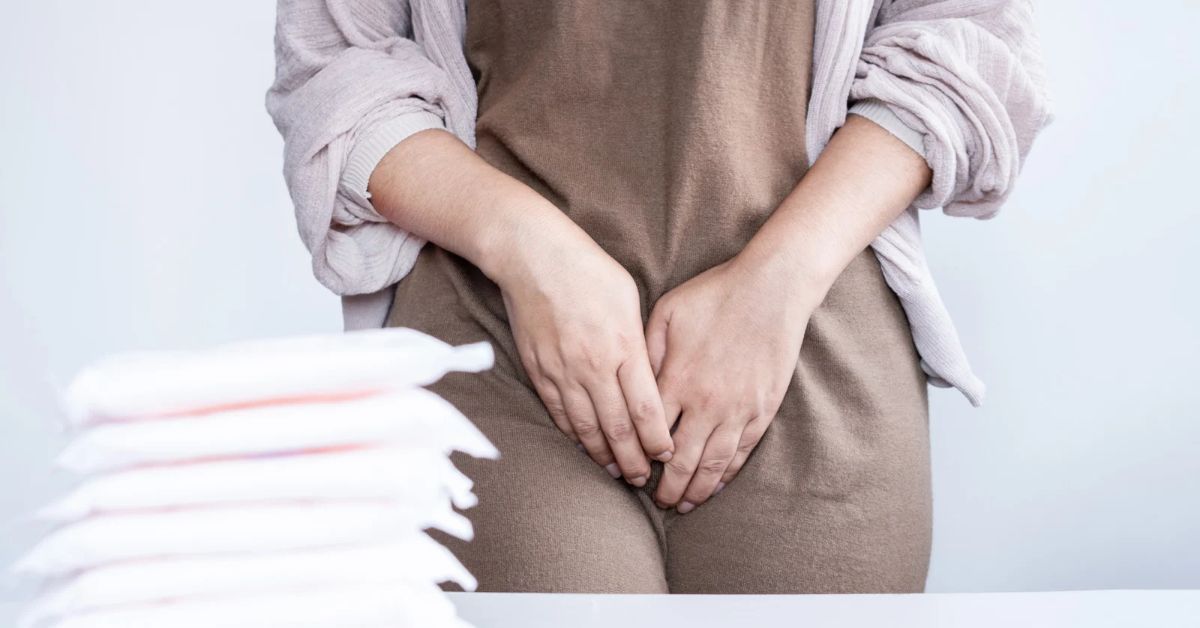 Donna con mani sul ventre e assorbenti in primo piano