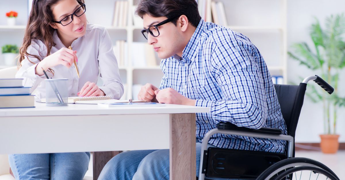Una donna e un uomo in sedia a rotelle lavorano insieme alla scrivania