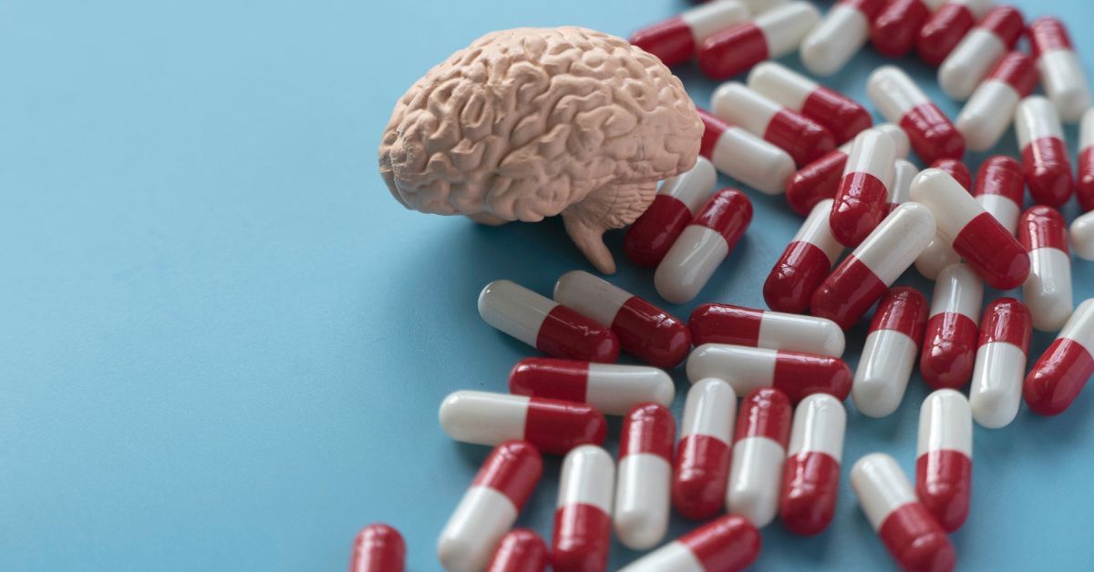 Pillole bianche e rosse con cervello su sfondo azzurro