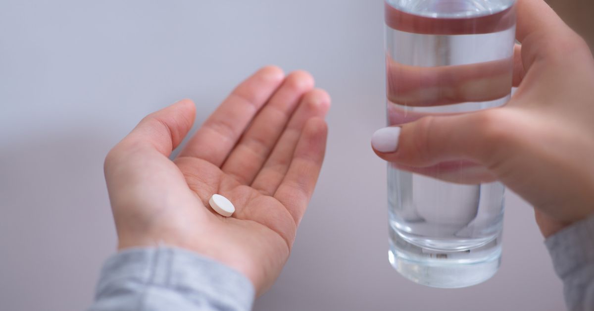 Mani con pastiglia e bicchiere d'acqua