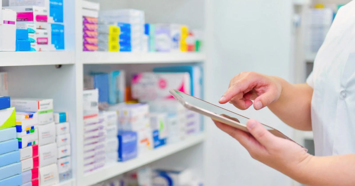 Scaffale con farmaci e farmacista che consulta un tablet