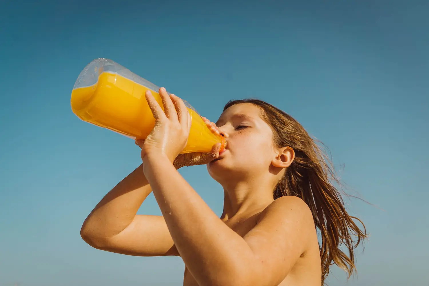Bambina che beve succo d'arancia
